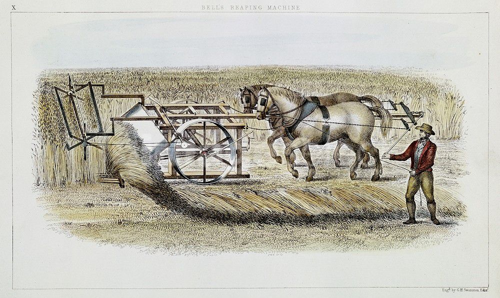 man guiding two horses pushing machine