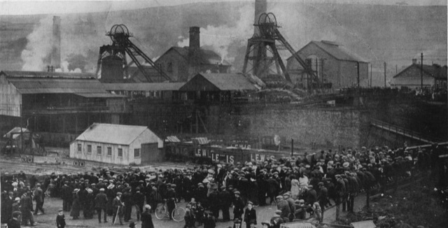 Black and white photograph of the Universal Colliery, taken from a raised position, and showing crowds waiting for news
