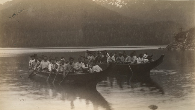 Photo of two large canoes with many rowers