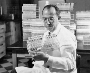 Dr. Jonas Salk looking at test tubes in his lab.